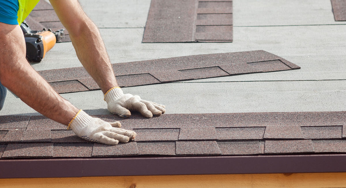 Worker repairing roof shingles