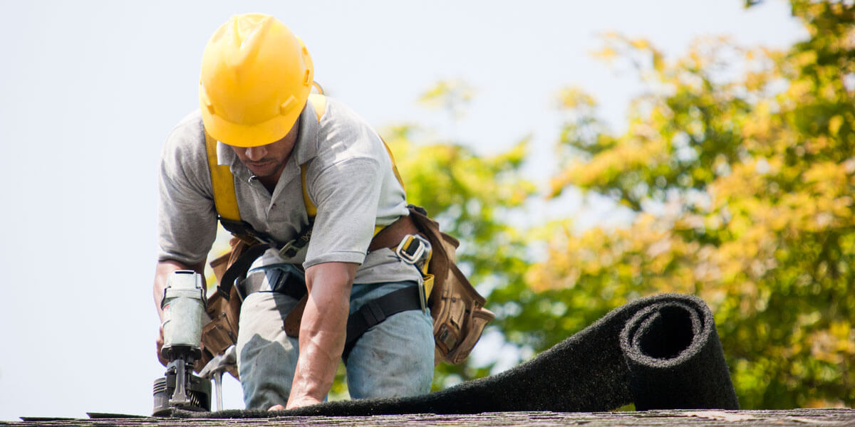 Roof worker attaching shingles to roof