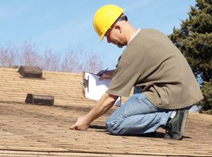 A person investigating roof shingles