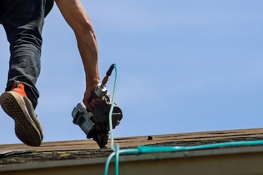 roofer holding nail gun while walking on roof